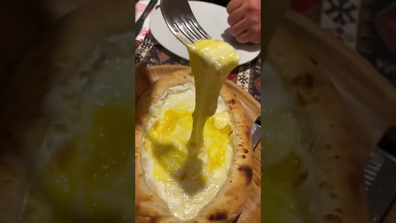 Тянущийся горячий сыр после разрезания хачапури пополам