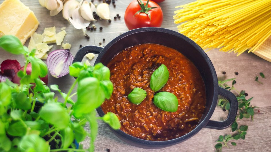 Мясной соус Болоньезе томится в глубокой кастрюле с мелкими овощами и томатами