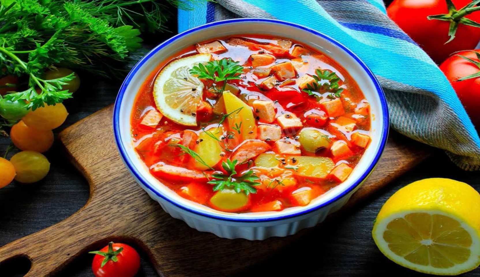 Подача солянки в тарелке с долькой лимона и свежей зеленью