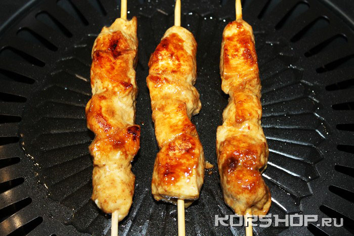 Куриные сатай на шпажках жарятся на горячей сковороде-гриль до золотистой корочки