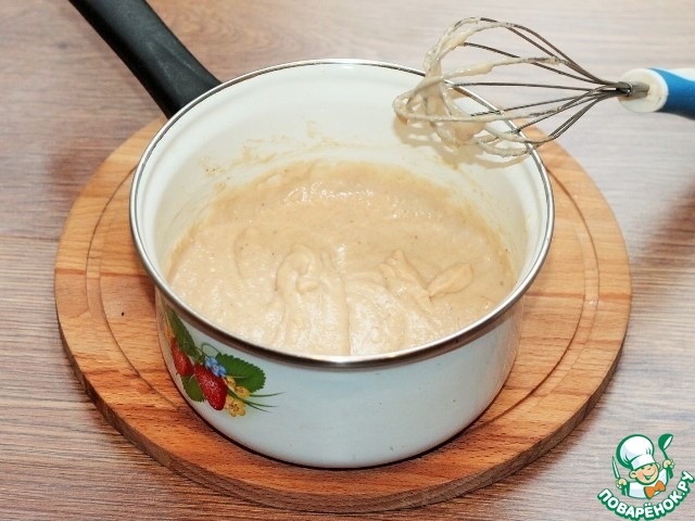 Венчиком взбивают арахисовый соус в кастрюле на слабом огне