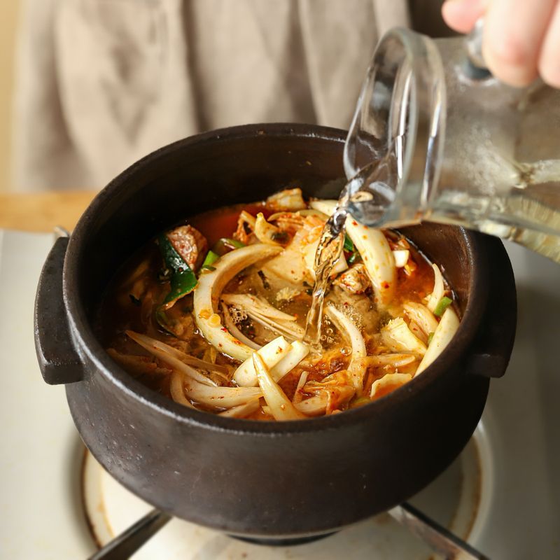 Обжарка кимчи с луком в кастрюле на плите